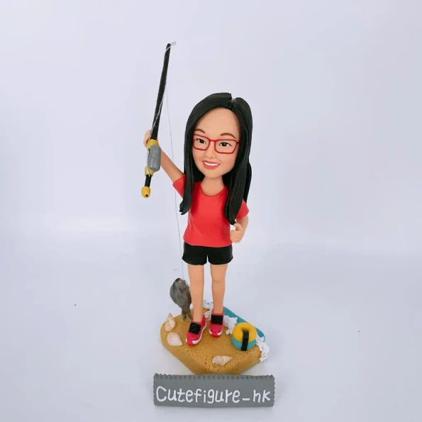一位戴眼鏡的女士的人像公仔，她正在海邊釣魚，並成功釣到一條魚。這是一份以個人愛好為主題的禮物。