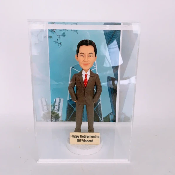 一個為名叫 Vincent 的男士訂製的榮休紀念品。模型主角是一位穿著西裝、雙手插袋的男士，他被放置在一個透明的亞加力膠盒內。前方的銘牌寫有『Happy Retirement to 靚仔 Vincent』，背景是一張以香港中銀大廈為主題的照片。