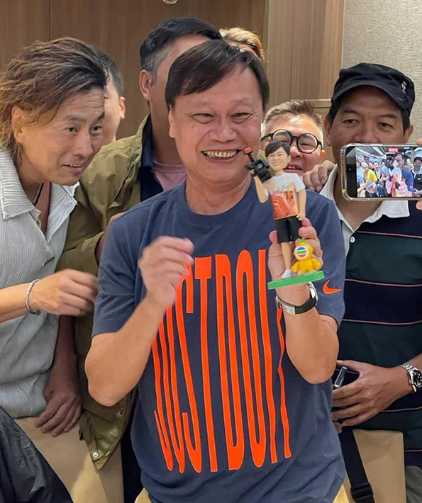 一張香港TVB演員在一眾好友的簇擁下，開心收到自己專屬人像公仔的照片。他高舉著這個根據他樣貌訂製、手持攝影機的人像公仔，笑容燦爛。這份禮物完美展現了送給tvb演員的創意與心意。