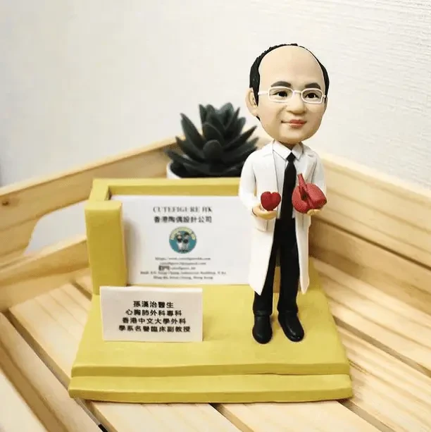 一位醫生造型的人像公仔，手持心臟模型，旁邊有名牌和醫療相關展示架