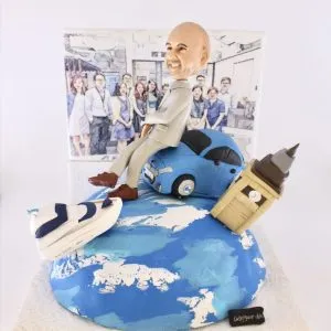 一個精緻的客製化榮休禮物場景模型。模型主角是一位笑容燦爛的光頭男士人像公仔，他輕鬆地坐在一輛藍色汽車上，汽車則停在一個地球模型頂端。地球上還有倫敦大笨鐘和跑鞋模型，象徵著旅行和個人興趣。背景是一幅素描風格的團隊合照，整個作品充滿故事性，是極佳的退休禮物選擇。