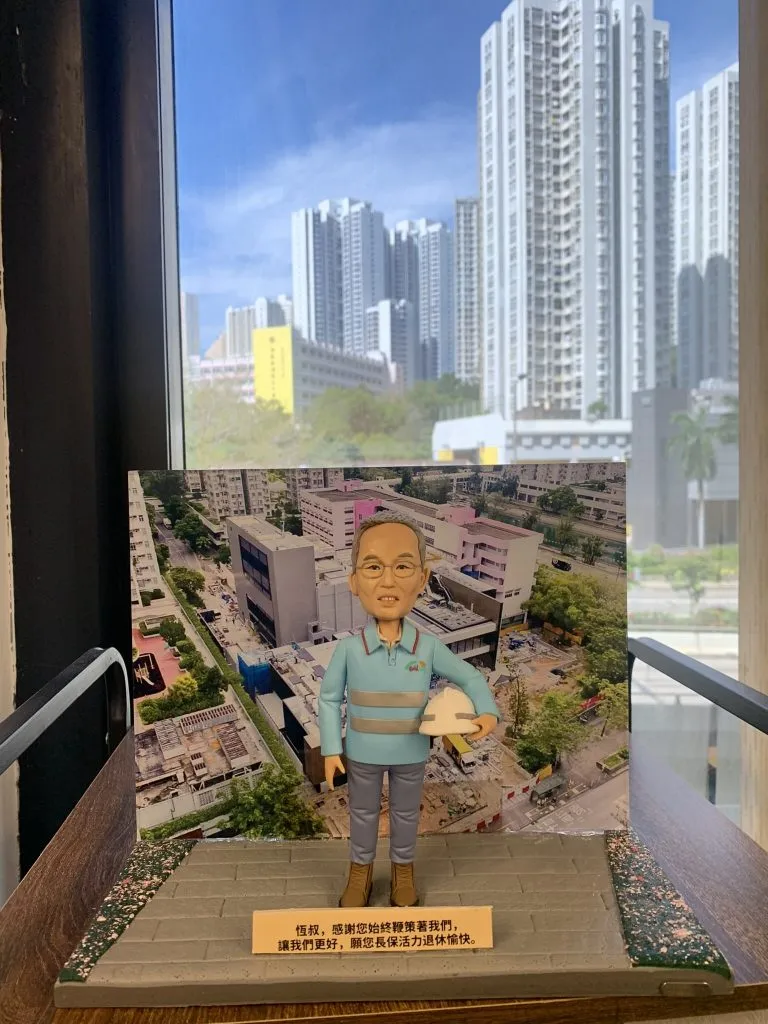 一個為被尊稱為「恆叔」的長者訂製的榮休禮物。模型主角是一位手持安全帽的人像公仔，他站在一個建築地盤的實景照片前。底座的銘牌上刻有團隊對他的感謝與祝福，是一份紀念其貢獻的工程師禮物。