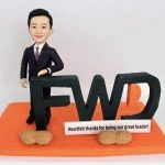 一款為FWD富衛保險的卓越領導者訂製的退休禮物人像公仔。公仔身穿西裝，自信地靠在巨大的FWD公司標誌上，橙色的底座上有一塊寫著「衷心感謝您成為我們偉大的領導者」的銘牌和兩顆象徵祝福的花生，是一份充滿敬意與巧思的禮物。