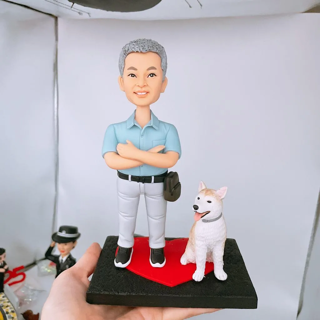 一款為醫生訂製的醫生人像公仔禮物，描繪了一位銀髮男士雙臂交叉，與他的愛犬一同站立在棒球壘板造型的底座上，展現其專業外的個人生活面貌。