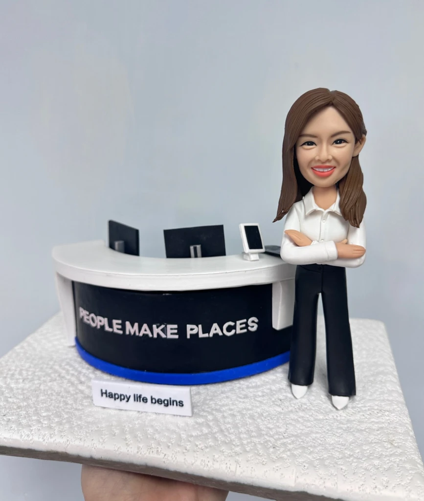 一款女性人像公仔，穿著白色襯衫和黑色長褲，雙手抱胸自信微笑，站在立體公司前台背景前，前台寫有「PEOPLE MAKE PLACES」字樣，底部有「Happy life begins」標語。這款人像公仔適合作為升職禮物、上司禮物或公司禮物，強調立體背景設計。