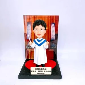一款客製化的教會詩班指揮人像公仔,呈現一位女老師身穿聖袍、手持指揮棒的模樣,是一份送給音樂事奉者的感謝禮物,可視為特別款的牧師人像公仔。