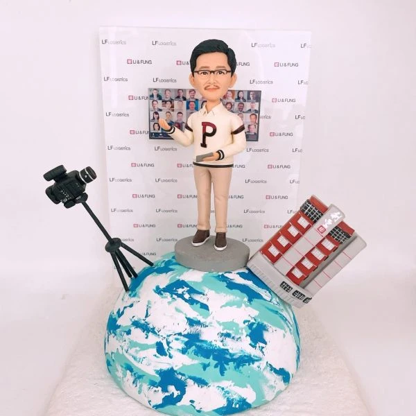 一款客製化的企業高層退休禮物，一位男士人像公仔站在地球模型上，場景包括專業攝影機、立體建築模型以及印有公司logo的背景牆，呈現全球領導者的風範。