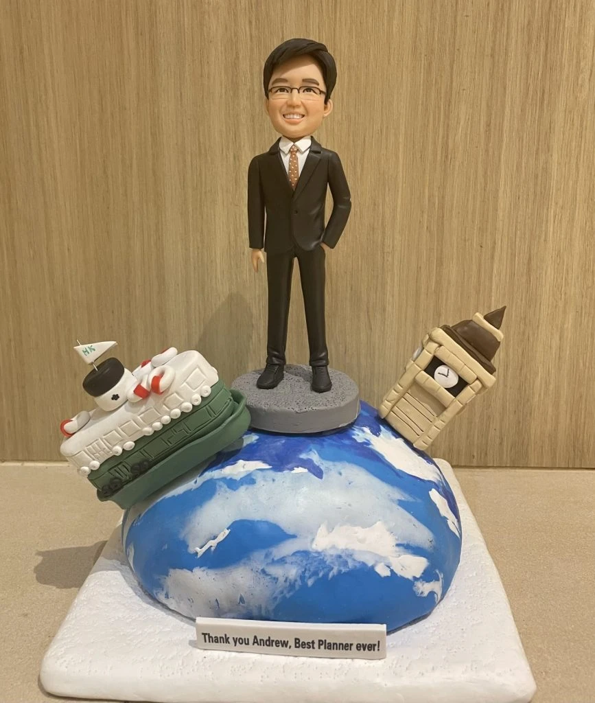 一款男士人像公仔作為合作夥伴禮物或退休禮物，他站在地球上，旁邊有香港天星小輪和倫敦大笨鐘的模型，象徵跨國合作。