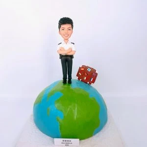 一尊以警察為主題的人像公仔站在地球造型的圓形底座上。公仔面帶笑容、雙臂交叉,穿著白色短袖制服上衣、肩章、黑色長褲與黑鞋,腰間配有皮帶與裝備套。身後靠著一只貼滿多國國旗貼紙的棕色行李箱,象徵退休後旅遊。底座前方有小牌匾寫著「恭喜榮休」與年份「2022」。背景為簡潔的白色牆面。