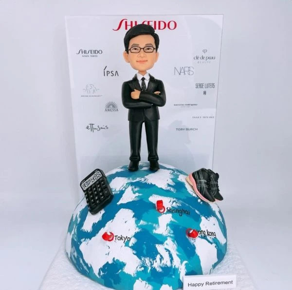 一款為企業高層訂製的退休禮物，一位西裝男士人像公仔站在地球模型上，場景中包含計數機、運動鞋等個人化配件，背景是一面印滿品牌商標的公司logo牆。