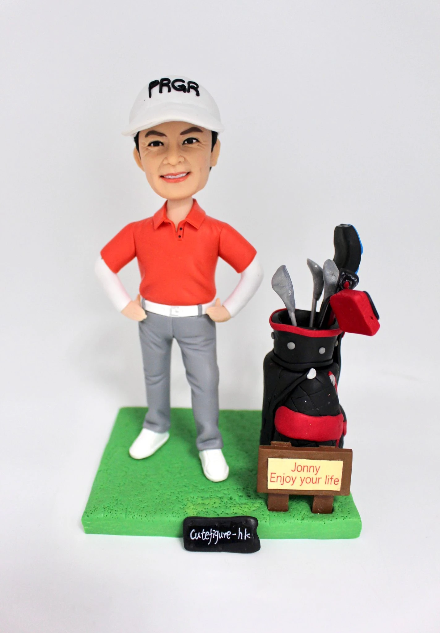 手工製作的高爾夫球運動人像公仔,穿著紅色球衣與白色帽子,身旁搭配精緻高爾夫球桿袋,展現運動熱情與專屬個人風格,為高爾夫球愛好者打造獨一無二的專屬紀念品。