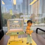 一款為兒科醫生Dr. S Fan LW訂製的榮休禮物。精緻的人像公仔身穿醫護服，慈愛地抱著一個新生嬰兒，身旁是一座高度還原的嬰兒保溫箱模型。這份醫生答謝禮物來自同事，充滿了對一位超級兒科醫生的敬意與祝福。