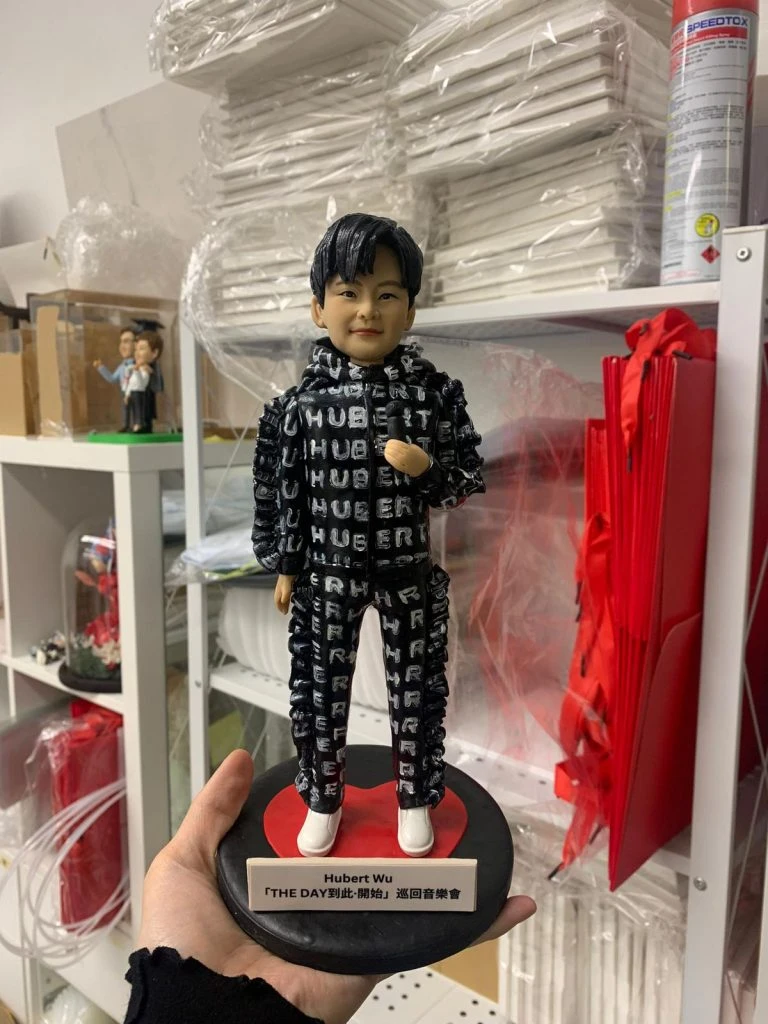 香港歌手胡鴻鈞（Hubert Wu）的訂製人像公仔，公仔身穿印滿其英文名的黑色舞台服飾，站在刻有其演唱會名稱的心形底座上。