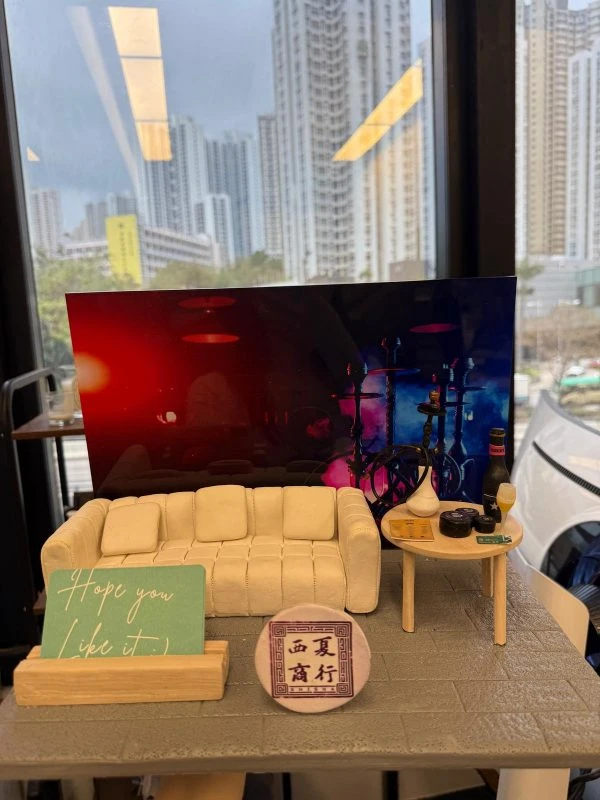 一個迷你ShiSha Bar場景模型，設有米白色梳化、小茶几、水煙壺、啤酒和寫上「西夏商行」的圓形招牌，是ShiSha Bar開張的特色場景擺設禮物。