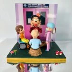 兒科病房場景中的醫生與醫護人像公仔：背景是醫院兒科病房入口（兒科病科病房 / Paed. Medical Ward），場景中有一位戴藍色手術帽、身穿粉紅制服的醫護公仔，陪伴兩位小病童──一位坐輪椅的小女孩、一位頭上有手術疤痕的男孩；中央則有一位扮小丑的表演者，用誇張表情逗笑病童。展示盒細節包含花朵、紅白蘑菇裝飾，呈現出溫馨療癒氛圍，適合作為醫生醫護主題的禮物或紀念公仔。