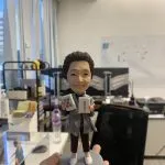 手工訂製的人像公仔，以長者形象為原型雕刻，手持兩張大型麻將牌「八筒」與「八萬」，展現真實細節與趣味設計。此人像公仔將麻將文化融入專屬個人化收藏，不僅象徵吉祥好運，也成為麻將愛好者與長輩專屬的獨特禮物。