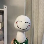 一款根據網絡顔文字設計的表情包立體公仔，白色蘑菇造型帶有得戚的微笑表情，是送給朋友的創意人像公仔生日禮物。