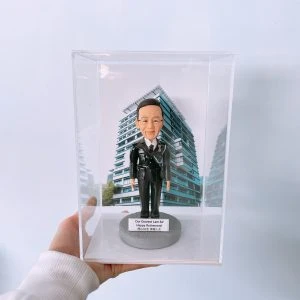 以黑色禮式制服呈現專業與榮譽，這款警察人像公仔置於透明亞加力展示盒，前牌刻上「Happy Retirement」祝福語，背板採用現代高層建築圖像，象徵城市服務場景。細節包含肩章、對講機與裝備刻畫，極具收藏與致敬意義，作為升遷或榮休禮物皆合適。