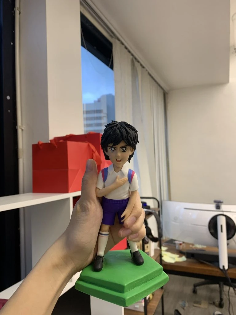 一款根據經典動漫人物《足球小將》戴志偉製作的人像公仔，公仔身穿球衣，手撫胸口，是送給粉絲的完美生日禮物。