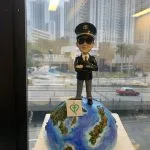 一款為機師退休設計的人像公仔，公仔身穿機師制服、戴太陽眼鏡，充滿自信地站在地球模型上，底座寫有「Happy Retirement 2024」，是完美的機師退休禮物。