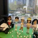高爾夫主題人像公仔，一組五位人物公仔擺設，包含坐在球車上的女性、舉手歡呼的球手、手持球桿的男女，以及站立於球袋旁的公仔。場景佈置有綠色草地、球車與多顆高爾夫球，展現打球氛圍。
