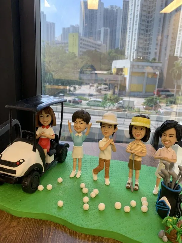 高爾夫主題人像公仔，一組五位人物公仔擺設，包含坐在球車上的女性、舉手歡呼的球手、手持球桿的男女，以及站立於球袋旁的公仔。場景佈置有綠色草地、球車與多顆高爾夫球，展現打球氛圍。