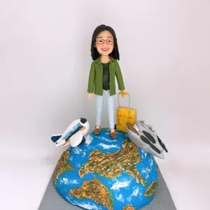 一款為女上司退休禮物客製的人像公仔,她拉著黃色行李箱站在地球上,旁邊有兩架飛機模型,充滿旅行元素。