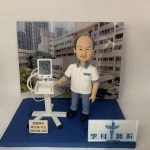 醫生人像公仔模型，身穿醫護制服，站立於醫院背景前方，手放在電子血壓計上，螢幕顯示血壓 109/74。此公仔為客製化醫護禮物，適合作為醫生退休紀念、醫護感謝或祝賀榮休的特別禮品。
