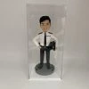 這是一份意義非凡的【晉升】賀禮，為一位年輕的【警務人員】訂製的專屬【人像公仔】。 從公仔的制服細節——尤其是肩上的一條銀色橫柴——我們可以推斷，這位【警務人員】榮升的職位是「見習督察」，這是其警隊生涯一個光輝的起點。公仔自信的笑容與輕鬆的站姿，正是這份喜悅的最佳寫照。 作品設計簡潔而專注，將所有焦點都集中在主角身上，底座的小花點綴，則象徵著他未來職業道路的無限生機。 這份禮物不僅僅是一件擺設，它更是一份認可、一個見證，紀念著他通過努力，成功邁入警官行列的決定性時刻。