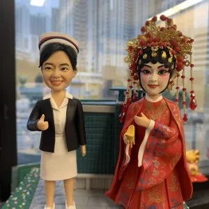 一位護士造型公仔身穿白色制服與黑色外套，頭戴護士帽，細節刻畫展現專業與溫暖特質；另一位戲劇新娘造型公仔身穿紅色婚禮服飾，搭配華麗金色與紅色頭飾，體現戲劇化舞台氛圍。兩款人像公仔均細緻雕刻，極具藝術感與收藏價值，適合作為榮譽表揚與感謝賀禮。