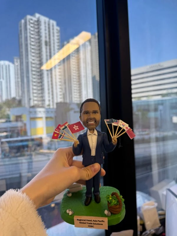 一款為外國老闆訂製的退休禮物人像公仔，公仔身穿西裝，手持由香港及亞洲各國國旗組成的扇子，是送給老闆退休的完美歡送禮物。