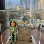 訂製醫生人像公仔｜醫護人員身穿綠色手術服及手術帽，坐在麻醉機旁，背後連接多個醫療監測屏幕與管線，細緻還原手術室場景。專屬醫生的醫護紀念公仔，適合作為禮物或退休紀念品。