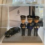 一款為三位高級警務人員訂製的晉升或退休禮物，包含三個身穿警隊禮服的人像公仔，站立在香港警察總部背景前，旁邊有一輛黑色座駕模型車。