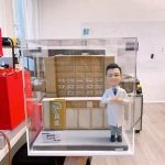 訂製中醫師人像公仔｜醫生穿著白袍站立於藥櫃前，櫃上標有川芎、黨參、當歸等中藥材抽屜，前方牌匾寫有「仁昌堂」。此公仔是專屬醫護禮物與醫生紀念擺設，象徵中醫藥專業與仁心仁術。