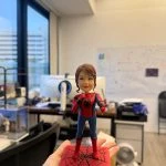 一款將女士頭像與蜘蛛俠身體結合的訂製人像公仔，她身穿蜘蛛俠戰衣，手持咪高峰，站在一個刻有「閃耀非凡舞台」字樣的紅色蜘蛛網地台上。