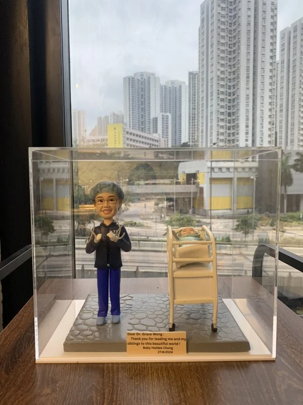 一款送給婦產科接生醫生黃醫生（Dr. Grace Wong）的醫生答謝禮物。精緻的人像公仔身穿手術服，微笑著站在一張嬰兒病床旁邊，床裡躺著一個新生嬰兒，銘牌上刻有來自嬰兒家庭的感謝語，是一份充滿溫情的紀念品。