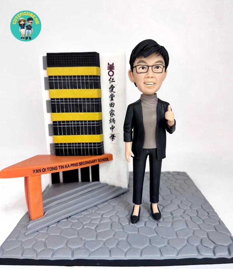 分割式「立體建築對比圖」。左側標註 BEFORE：田家炳中學的校舍外觀仰角照，米色長條教學樓連接多層窗戶與外置冷氣機，前景有高大綠樹，屋頂見欄杆與梯間結構。右側標註 AFTER：手作 diorama 作品，灰色石板紋底座上重現校門一隅：黑黃相間的條帶立面、灰色階梯入口、橙色橫樑上以英文刻有「YAN OI TONG TIN KA PING SECONDARY SCHOOL」，旁有白色豎立招牌寫上中文校名。場景右側站著一位教職風格的人像公仔，短髮、戴眼鏡、穿黑色外套與深色長褲，右手比讚，呈現溫暖親切的祝賀氛圍。