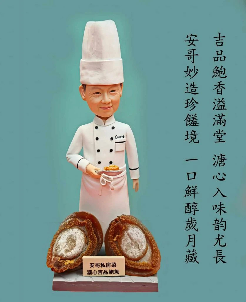 一位穿白色高帽與雙排扣廚師服的人像公仔，胸前有「Encore」名牌，手托一碟鮑魚；腳前擺放兩顆大型鮑魚模型與小木牌，背景為綠色牆面並有直排中文文案。