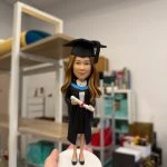 女畢業生公仔穿學士袍與方帽，手持文憑站在白色圓底座，畢業禮物可客製姓名與校色