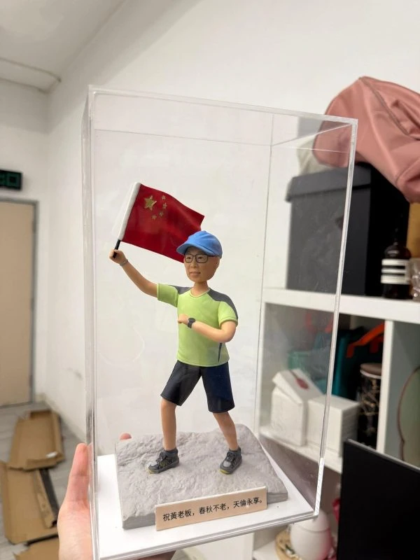 登山運動公仔戴帽揮舞紅旗，立於岩地底座並置於透明展示盒，壽宴與里程碑禮物推薦
