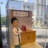 心胸肺外科醫生主題人像公仔穿白色醫師袍與手術服，雙手抱胸站在診間場景，旁有肺部模型與仁心仁術匾額，醫師開業與升遷客製禮
