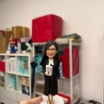 女律師主題人像公仔穿黑色法袍與白色領巾，手持法律判例手冊站在白色圓底座，律師節與執業授證客製禮