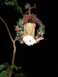 一個小巧精緻的聖誕花圈掛在樹枝上，以松果、紅色漿果和白色棉花裝飾，充滿節日氣氛，是聖誕佈置的好靈感。
