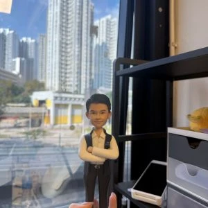 CUTEFIGUREHK 客製化香港警察人像公仔。公仔身穿白恤衫搭配深色背心，胸前佩戴「POLICE」字樣委任證，雙手交叉胸前展現自信。底座印有「戴琮熹督察 祝一帆風順 步步高陞 警隊華仁仔仝人」的專屬祝福語。這是一份專為紀律部隊人員升職或調職度身訂造的紀念禮物。