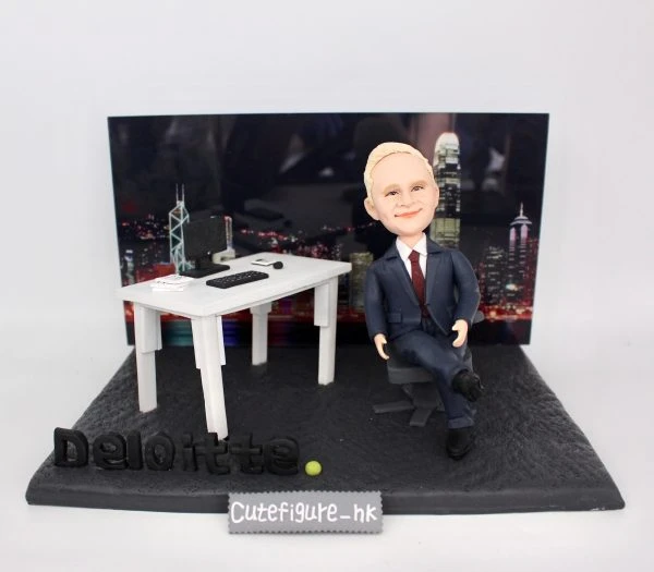 一款為外國老闆訂製的退休禮物人像公仔，公仔是一位穿西裝的男士，坐在辦公室的立體場景中，背景是香港維港背景夜景，底座上有Deloitte公司標誌。