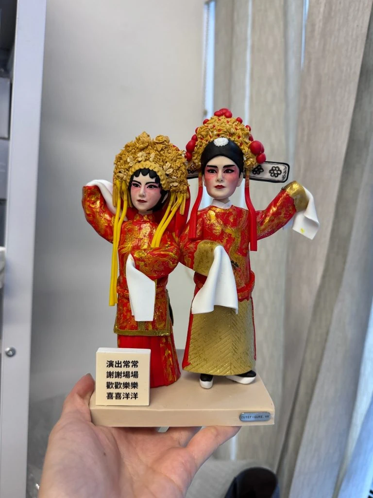 一對以戲劇角色為主題的人像公仔，身穿精緻紅色與金色華服，搭配繁複的傳統戲曲頭飾與妝容，展現舞台風華與戲劇特色。公仔細節生動，手持白布飄帶，還原戲曲動作神韻，是展現戲劇藝術與角色魅力的獨特收藏與賀禮選擇。