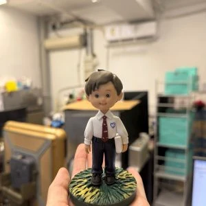 校園主題學生公仔立於草地圓底座,白色制服配紅色領帶與書本,入學升學畢業紀念客製