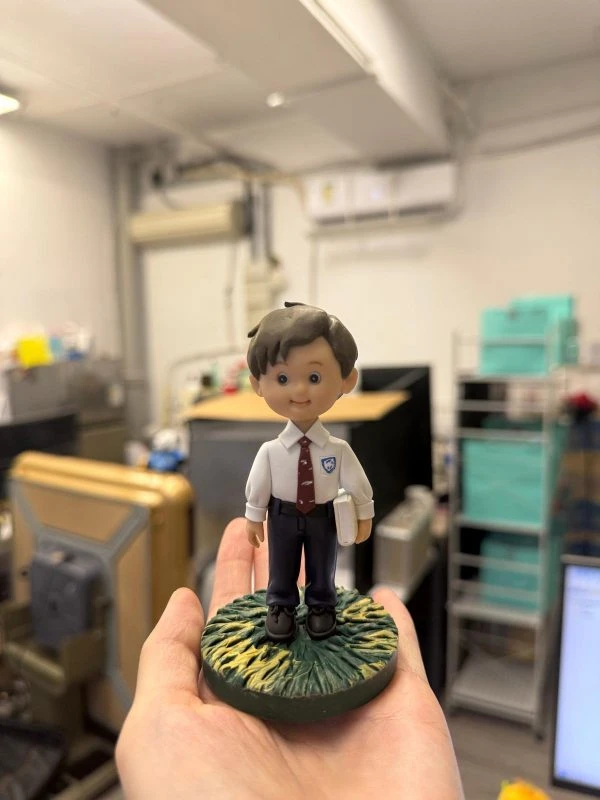 校園主題學生公仔立於草地圓底座，白色制服配紅色領帶與書本，入學升學畢業紀念客製