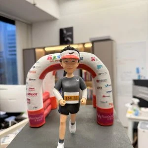 馬拉松跑手人像公仔，跑步姿勢走向印有贊助商Logo的終點拱門，胸前配上客製化號碼布