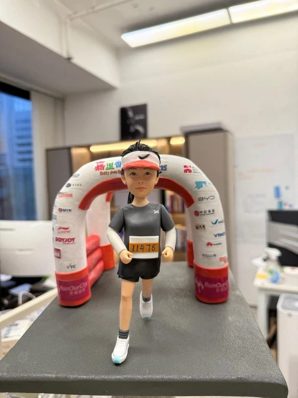 馬拉松跑手人像公仔，跑步姿勢走向印有贊助商Logo的終點拱門，胸前配上客製化號碼布